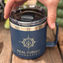 Load image into Gallery viewer, Blue mug with 'Seal Future Foundation' logo held by a hand on a wooden surface.
