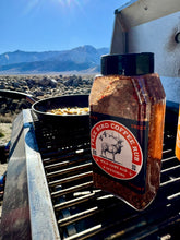 Load image into Gallery viewer, Bottle of Tree Bird Coffee Rub on a grill with a mountainous landscape in the background, Free Bird Coffee Seasoning and Rub, Coffee infused seasoning, coffee rub, the best seasoning, the best rub, the best coffee rub
